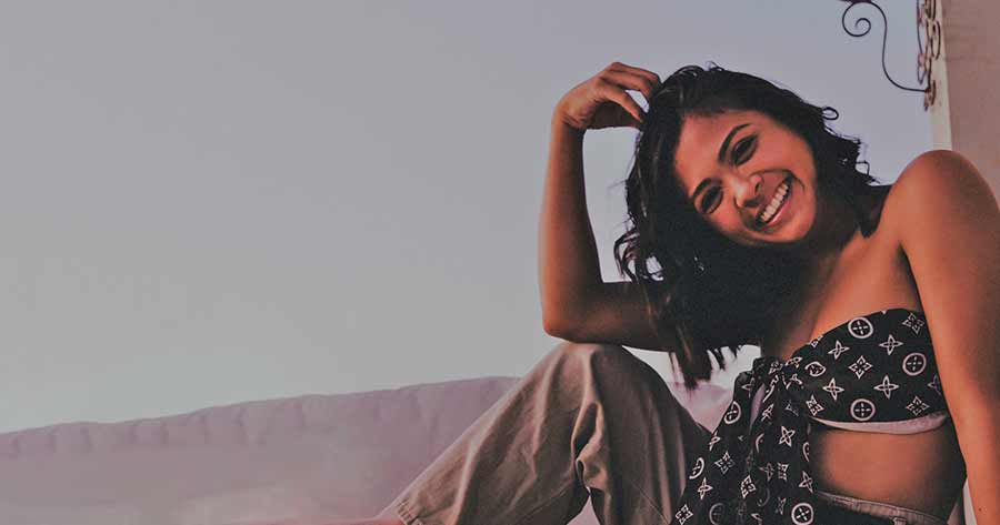 A photo of a smiling woman sitting on a couch